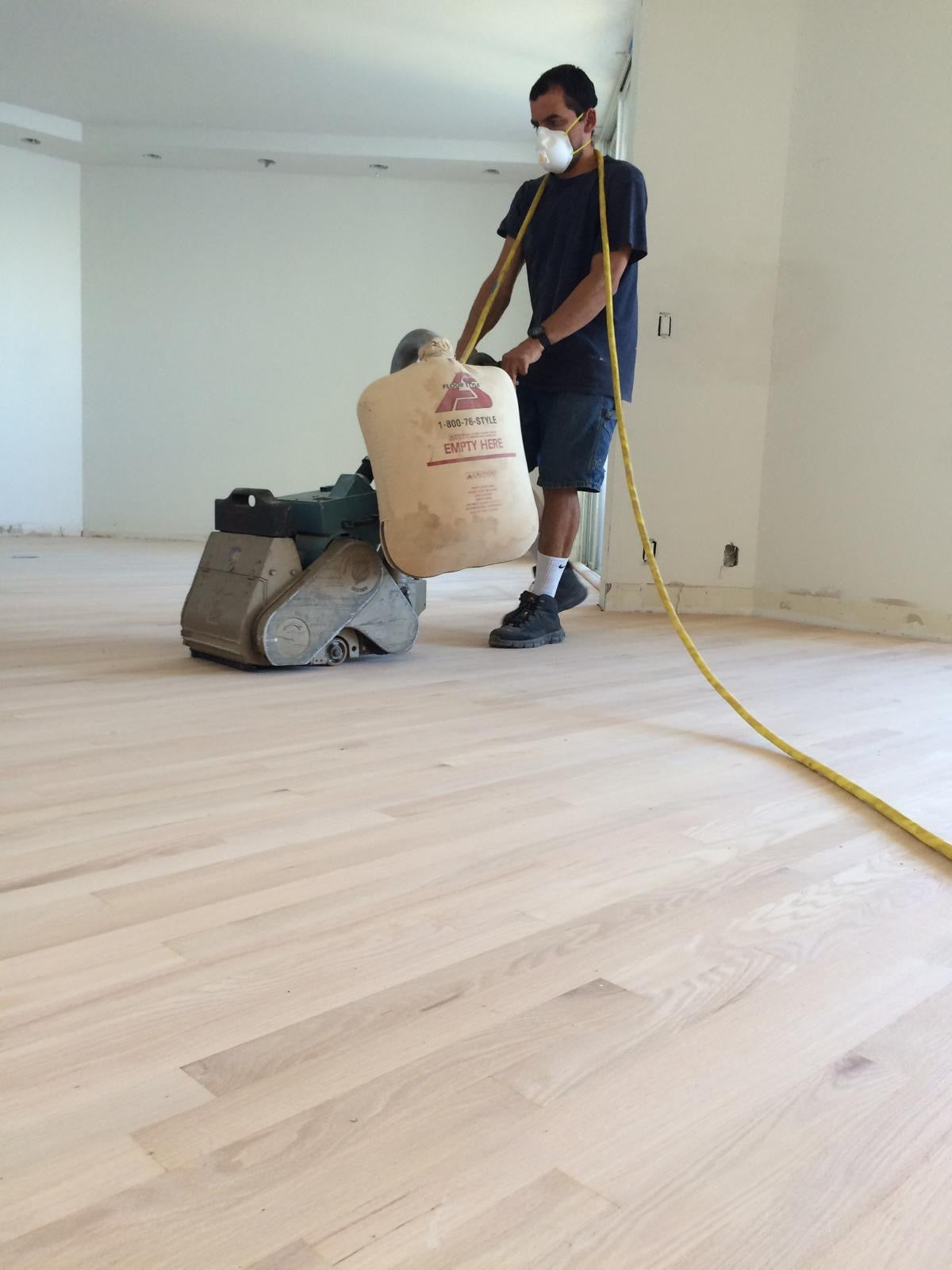  Close-up of a sanding machine smoothing out a hardwood floor before staining.