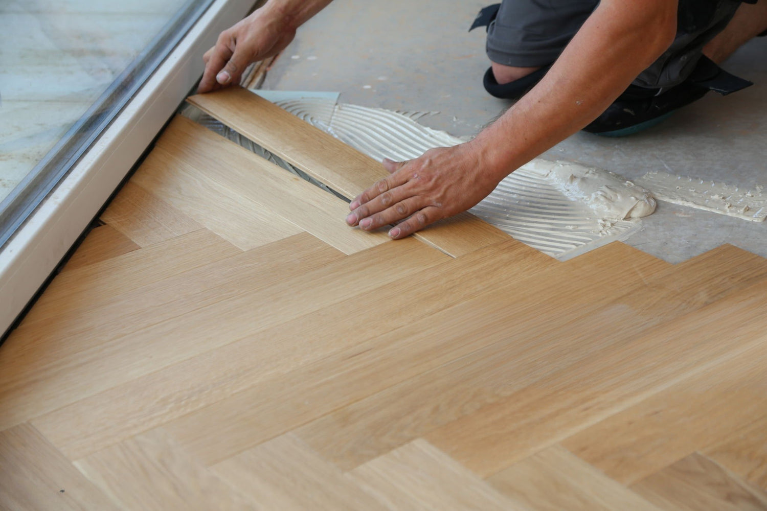 Herringbone floor being installed using glue down method